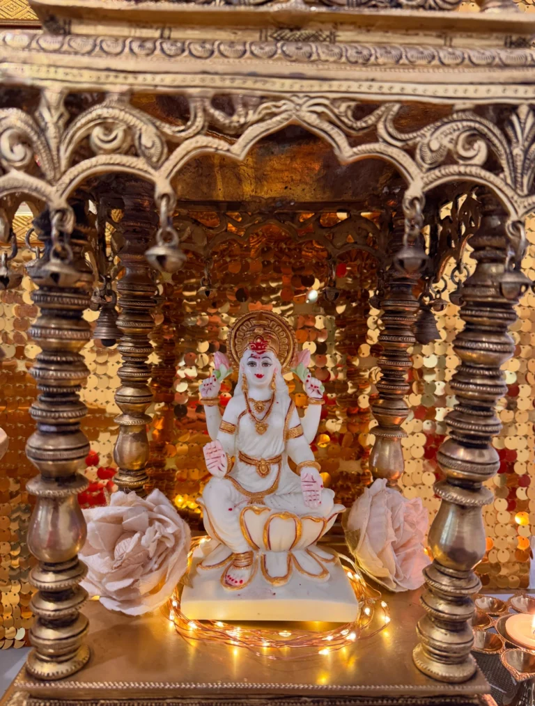 A beautifully handcrafted solid brass temple from India, created to house Sri Lakshmi, with the goddess seated amid intricate traditional detailing and glowing lights.