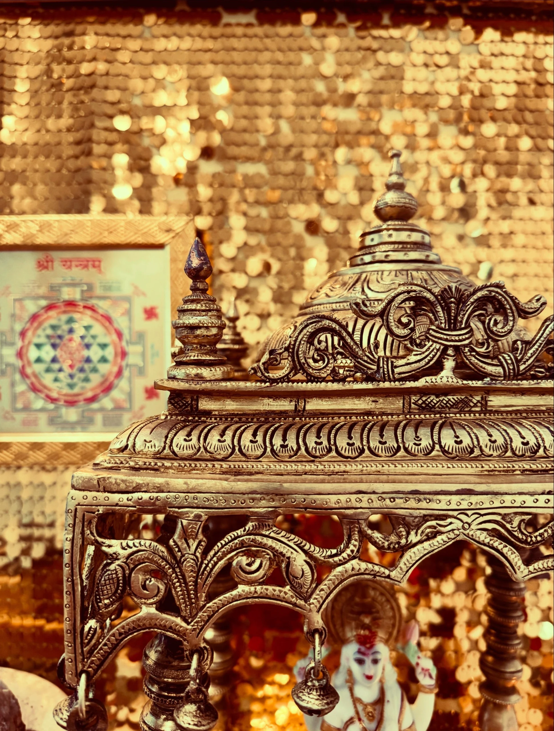Handmade solid brass Indian temple housing a white Sri Lakshmi idol, surrounded by ornate carvings, golden decorations, and warm lights.